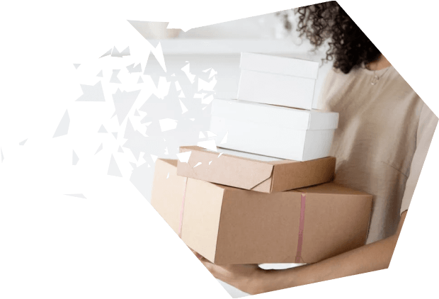 A smiling woman holding a stack of cardboard and white boxes, standing indoors in a minimalistic setting, representing order management or delivery services.